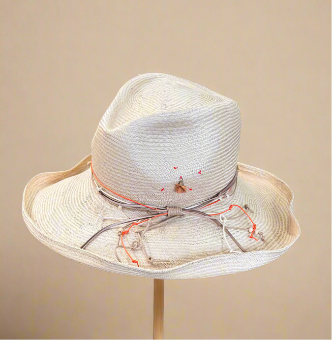 Light straw hat with white and orange decorative ribbon on a beige background
